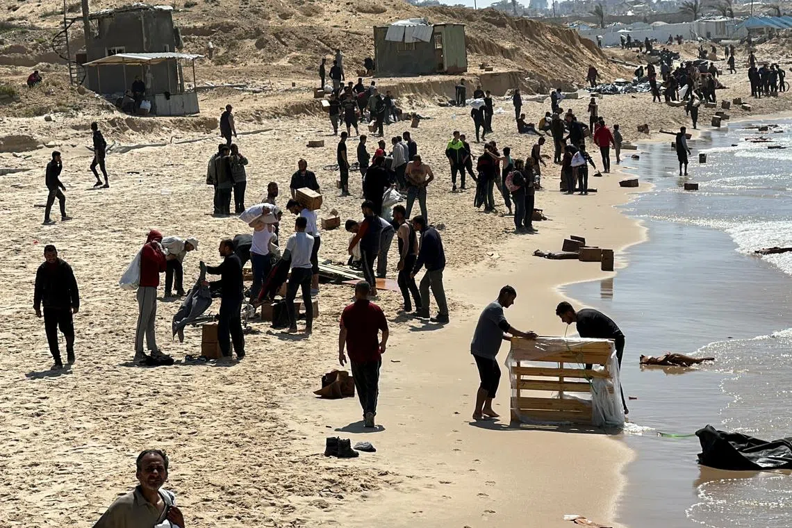 Palestinians gather on a beach as they collect aid airdropped by an airplane, amid the ongoing conflict between Israel and Hamas.