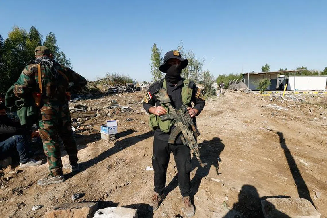 FILE PHOTO: Fighter of the Iraqi Kataib Hezbollah militia group stands the site of a U.S. airstrike, in Hilla, Iraq December 26, 2023. REUTERS/Alaa al-Marjani