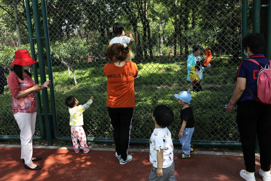 Children play next to adults at a park in Beijing, China June 1, 2021. REUTERS/Tingshu Wang/File Photo