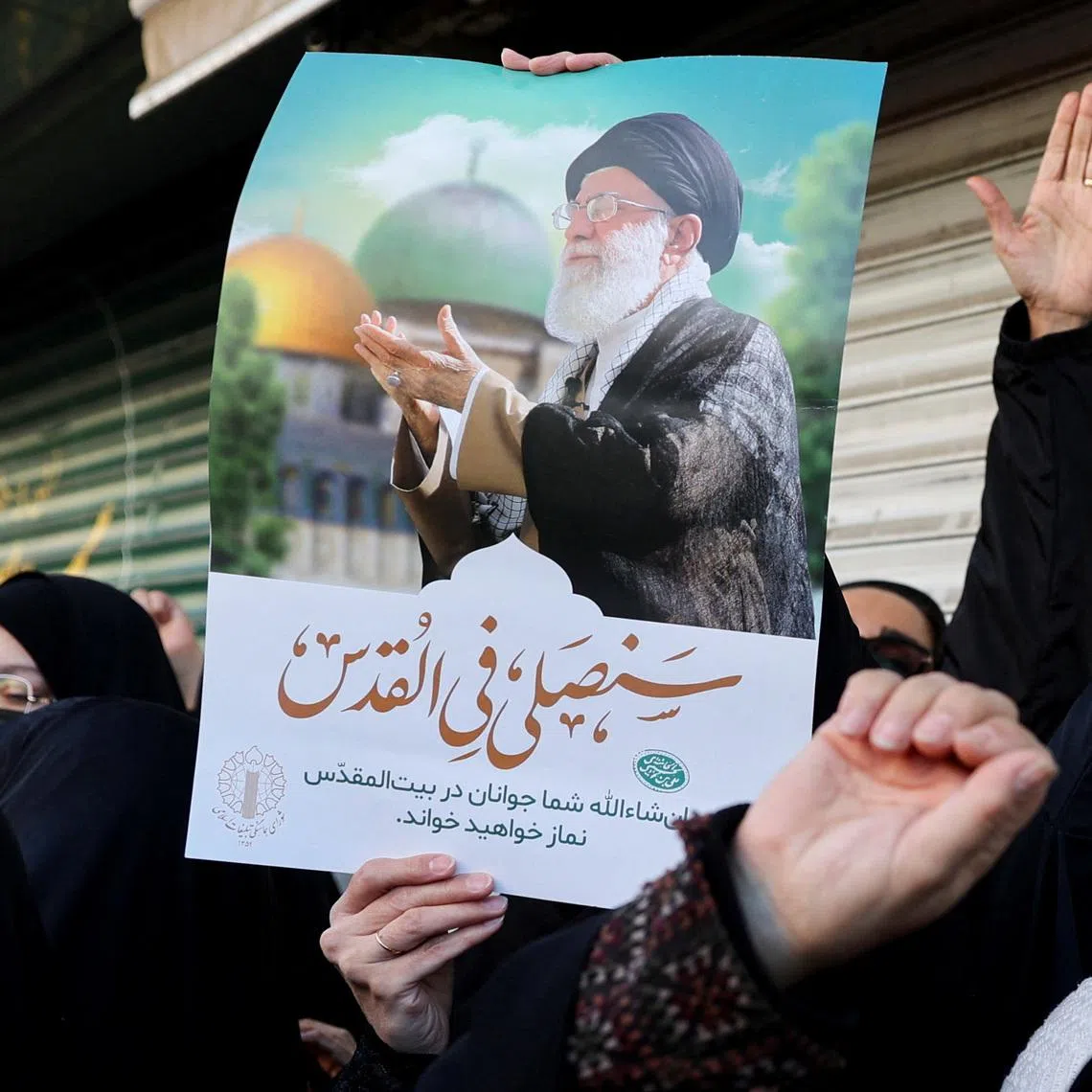 A woman holds a poster with the picture of Iran's Supreme Leader Ayatollah Ali Khamenei as people gather after Khamenei was killed in Israeli and U.S. strikes on Saturday, in Tehran, Iran, March 1, 2026. Majid Asgaripour/WANA (West Asia News Agency) via REUTERS