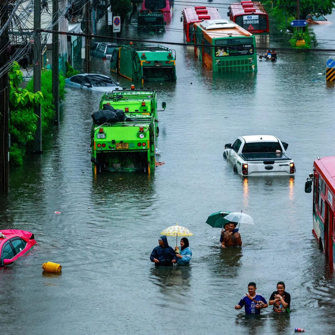 People wade through a flooded street during heavy rain in Bangkok, on Sept 26.