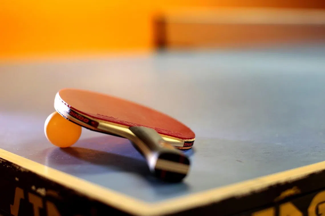 Table tennis paddle and ball on a table.