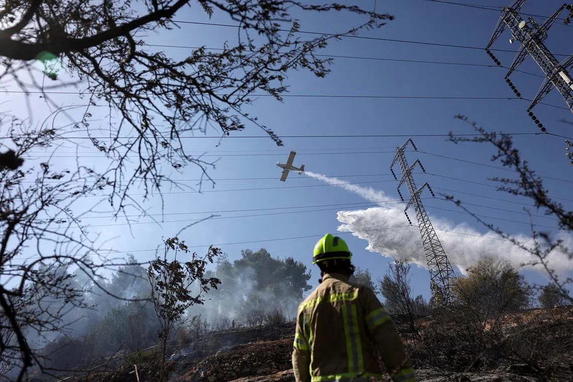 A firefighting plane dispersing fire retardant as it assists in extinguishing a fire near Motza on the outskirts of Jerusalem, Aug 24, 2025.