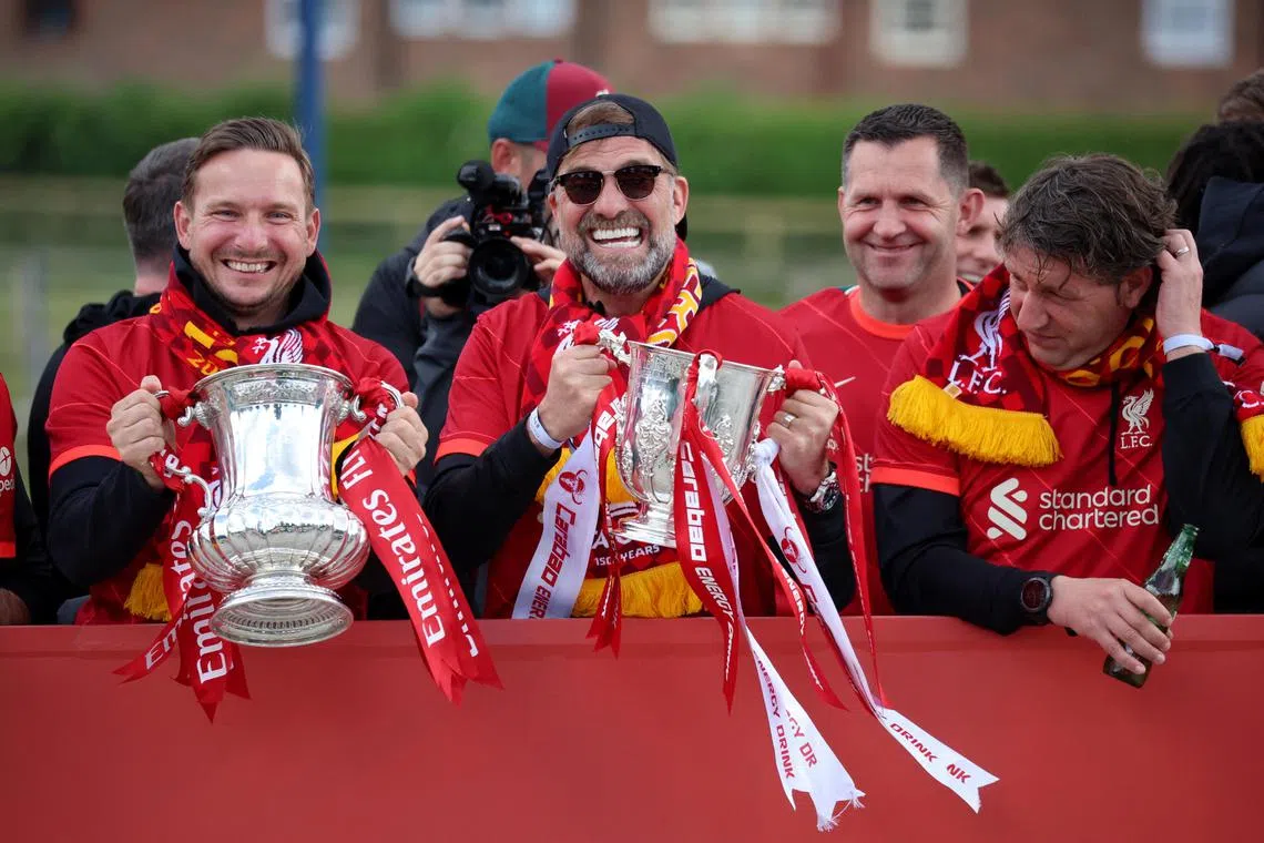 Liverpool manager Jurgen Klopp and assistant manager Pepijn Lijnders celebrate with the FA Cup and the League Cup during a victory parade in May 2022.