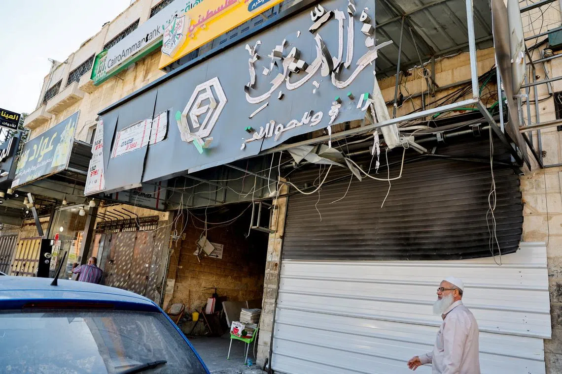 A man walks past a closed exchange office building that was damaged and targeted during an Israeli military operation, in Tulkarm, in the Israeli-occupied West Bank, May 16, 2024. REUTERS/Raneen Sawafta