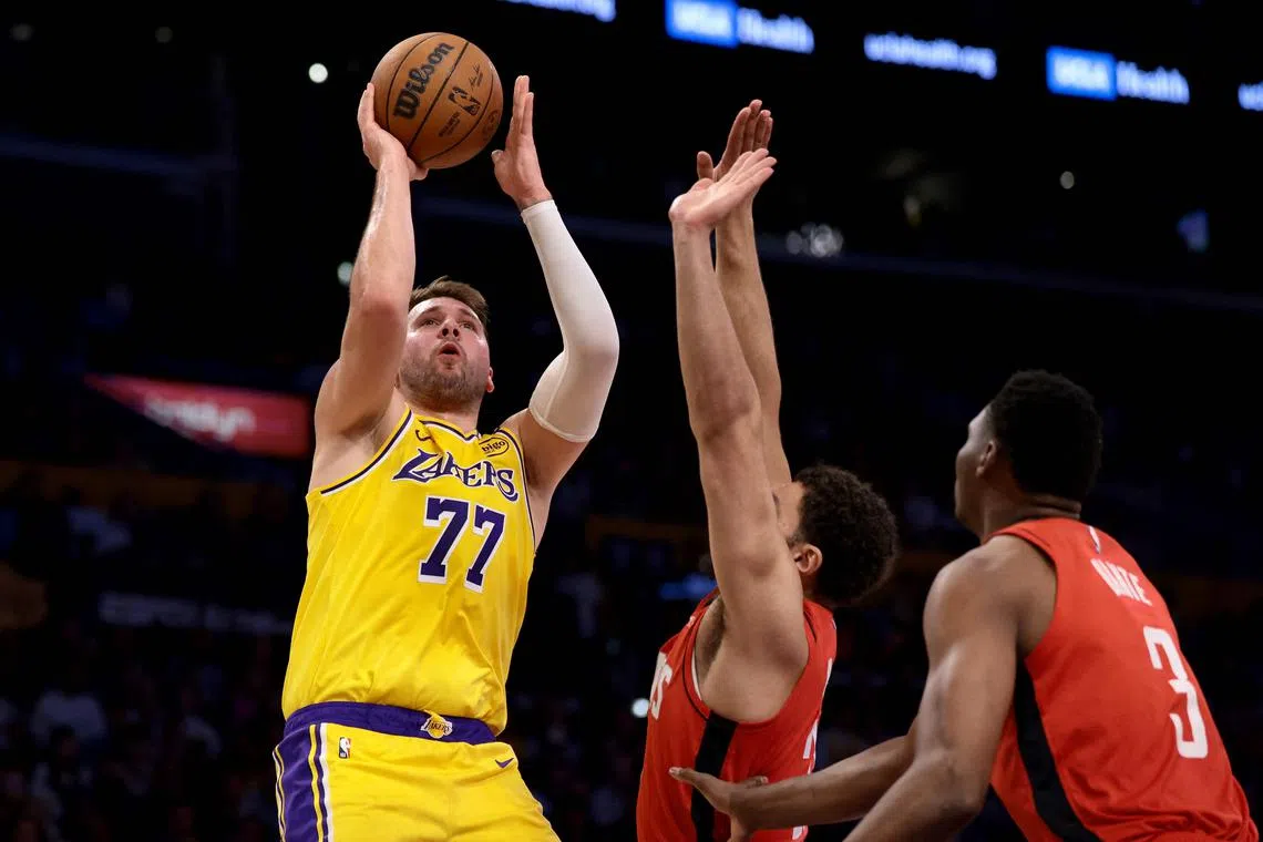 Luka Doncic of the Los Angeles Lakers shoots the ball against David Roddy and N'Faly Dante of the Houston Rockets.