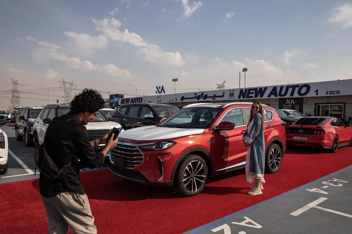 A Russian-speaking sales agent poses for social media content at one of the dealerships in the car market on the outskirts of Dubai.