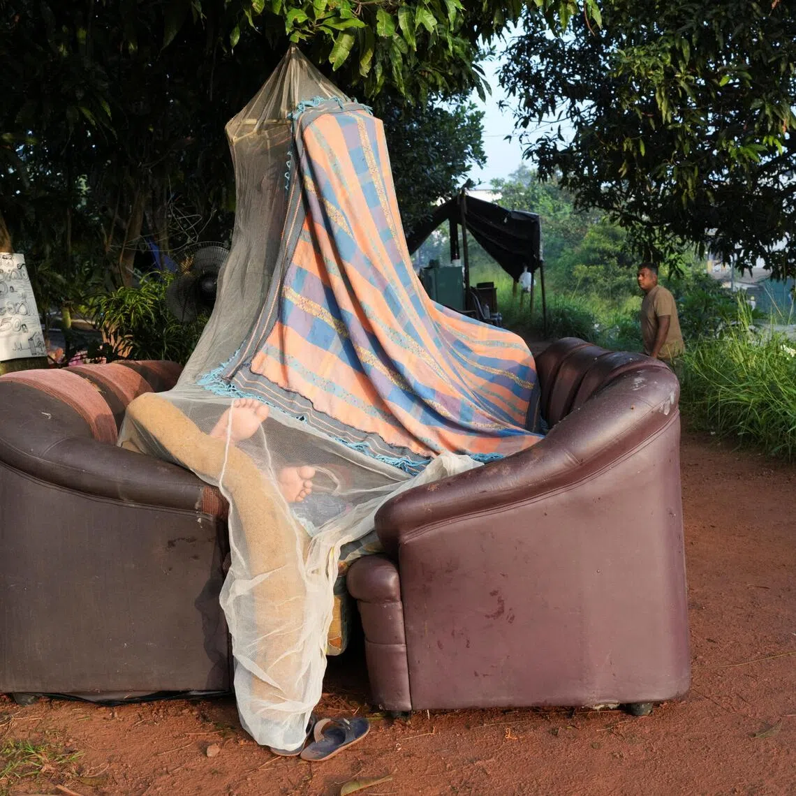 A person sleeps inside a makeshift tent made by a mosquito net and sofas along the banks of Kelani River, following Cyclone Ditwah in Peliyagoda, Sri Lanka, December 1, 2025. REUTERS/Thilina Kaluthotage 