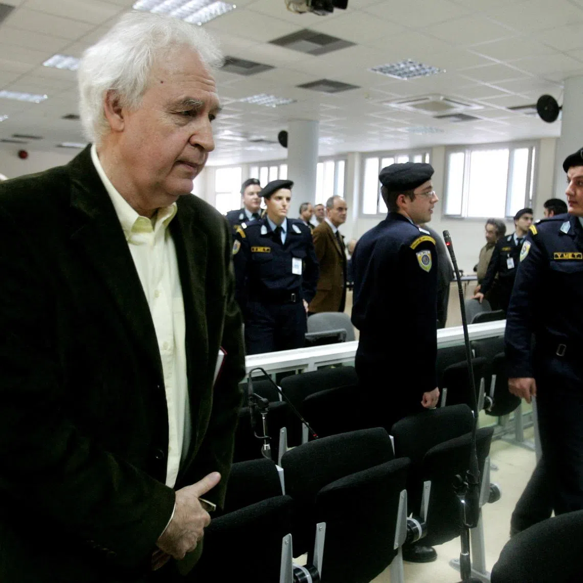 FILE PHOTO: Alexandros Giotopoulos (L), leader of Greece's notorious November 17 urban guerrillas, stands inside a court room in Korydallos prison, a few kilometres west of Athens December 2, 2005. The 15 members of the group returned to court on Friday to appeal multiple life sentences handed down two years ago for a 27-year killing spree with Giotopoulos demanding his full acquittal. REUTERS/Yiorgos Karahalis/File Photo
