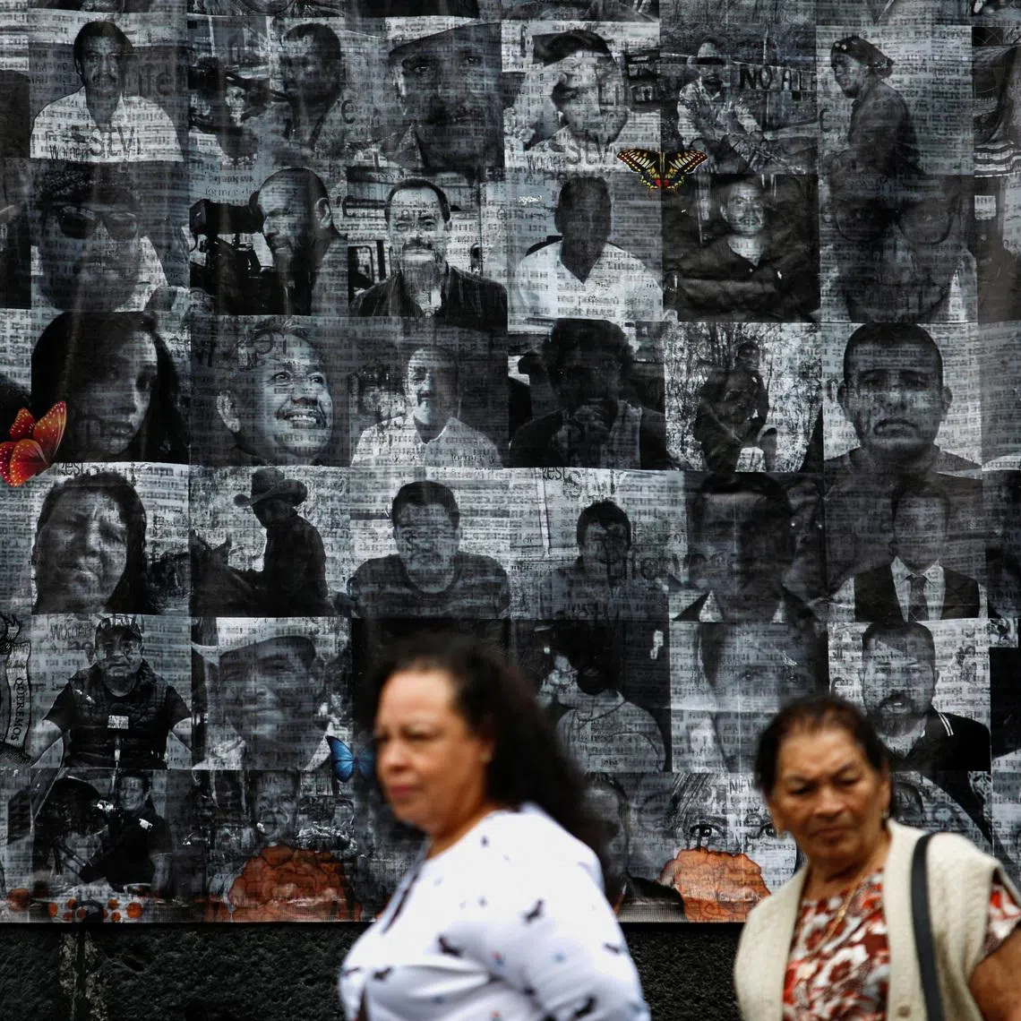 People walk by pictures of murdered journalists and activists displayed on an altar on the eve of the Day of the Dead in Mexico City, Mexico, October 31, 2022. REUTERS/Gustavo Graf/File Photo