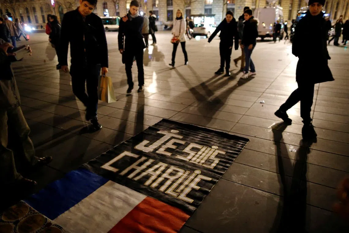 FILE PHOTO: People gather on the Place de la Republique square to pay tribute to the victims of last year's shooting at the French satirical newspaper Charlie Hebdo, in Paris, France, January 7, 2016. REUTERS/Stephane Mahe/File Photo