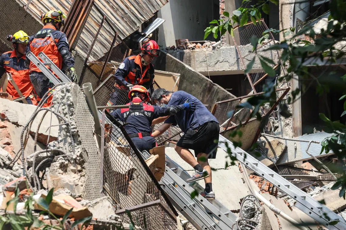 Emergency workers assisting an earthquake survivor after he was rescued from a damaged building in New Taipei City on April 3, 2024.