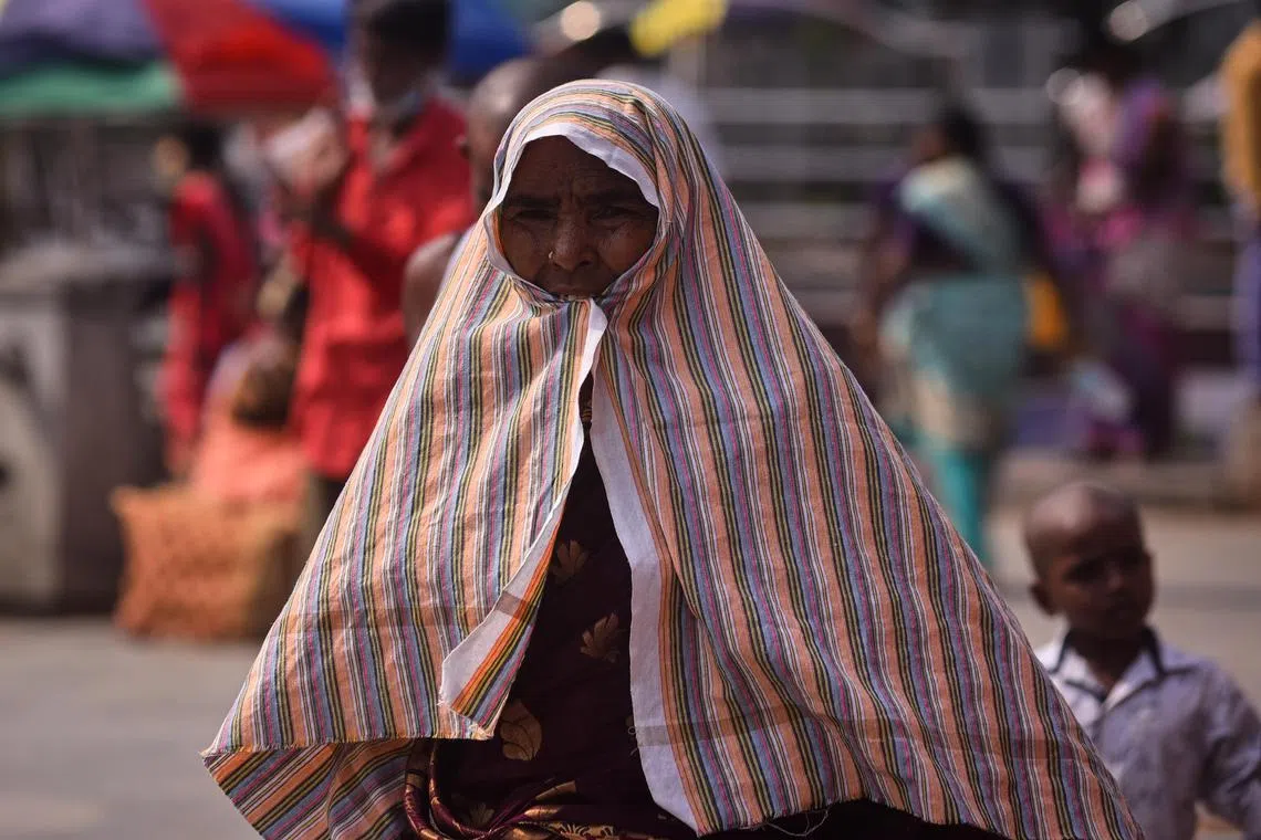 A woman covers herself with a piece of cloth for protection from the sun, during a hot afternoon in Chennai, India, on May 15.