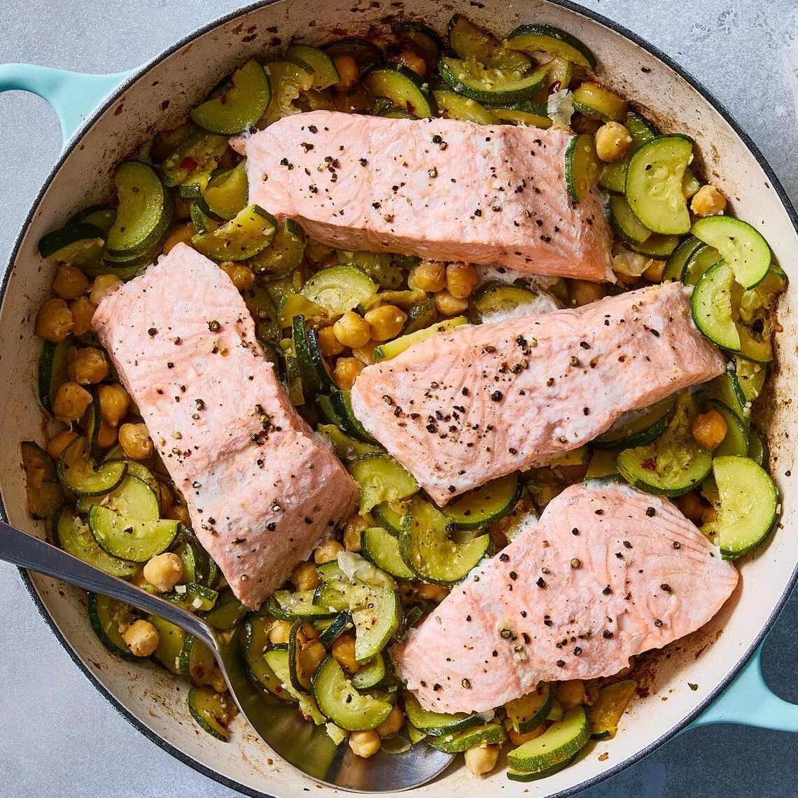 Salmon with olive oil-braised zucchini and chickpeas. Slow-cooking zucchini in garlicky olive oil intensifies their natural sweetness and gives them a silky texture. Food styled by Barrett Washburne. (Bryan Gardner/The New York Times)