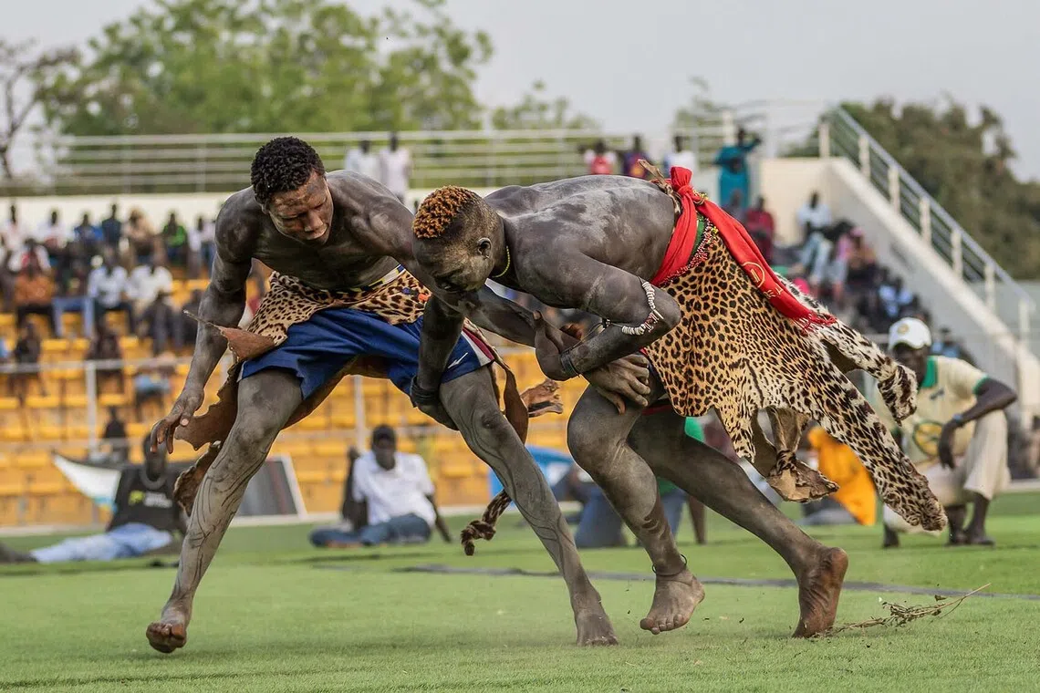 TOPSHOT - Wrestlers grapple in an effort to throw each other to the ground during a peace-focused cultural wrestling match in Juba on December 20, 2025. Traditional wrestling is a popular sport in South Sudan, with several events held throughout the year that highlight efforts to ease tensions and promote unity through shared cultural heritage, bringing communities together in a spirit of peace and reconciliation. (Photo by Isaac Buay / AFP)