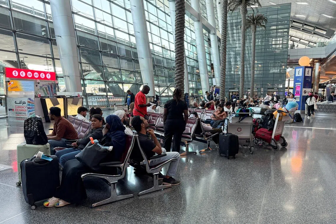 FILE PHOTO: People sit at Hamad International Airport after Qatar reopened its airspace following a brief closure in the wake of Iran’s missile attack on Al Udeid Air Base on Monday, in Doha, Qatar, June 24, 2025. REUTERS/Stringer/File Photo