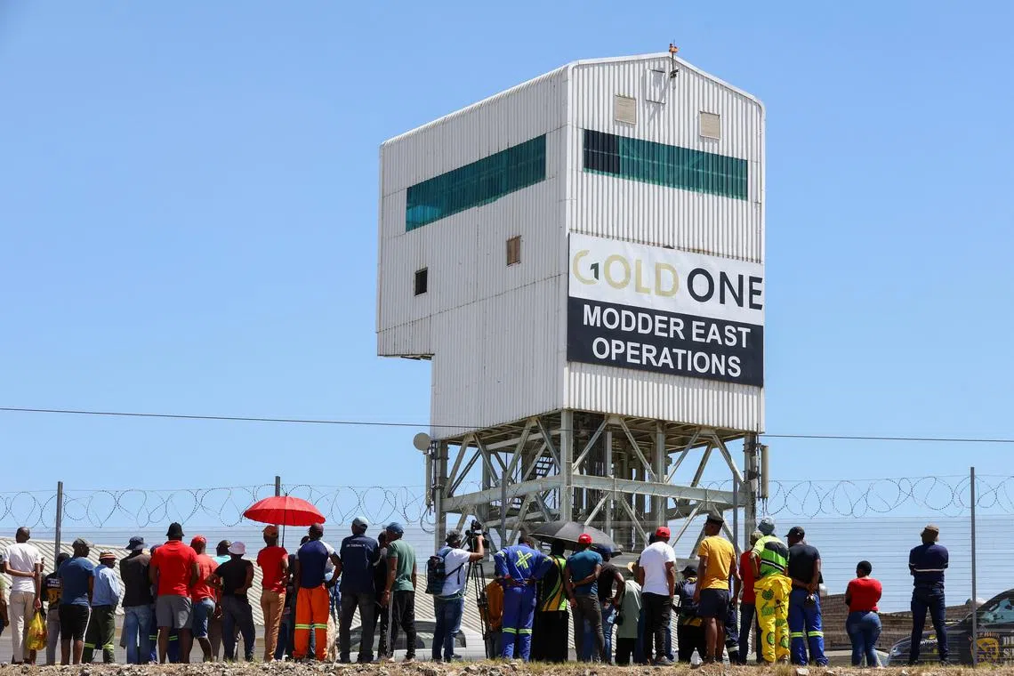 Family members and colleagues wait outside a Gold One mine in October 2023, after more than 500 miners became trapped underground for almost three days amid a labour unions standoff.