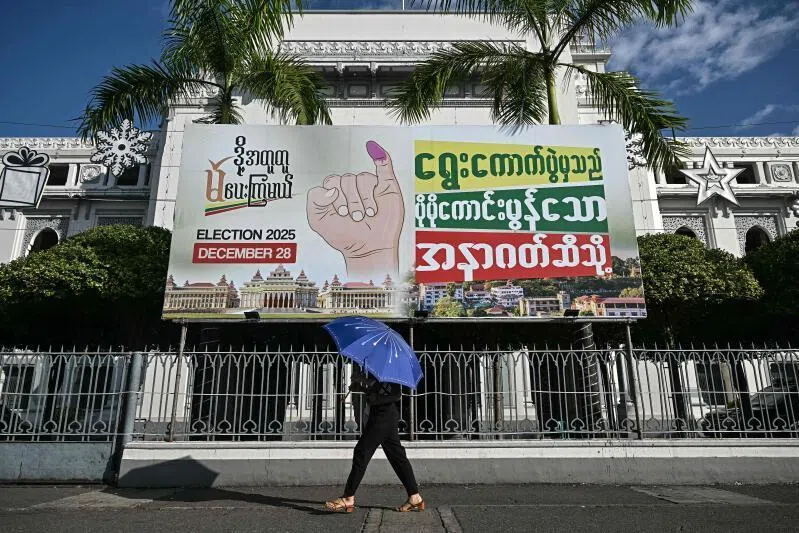 A woman walking past an election banner during the first phase of Myanmar's general election in Yangon on Dec 28.