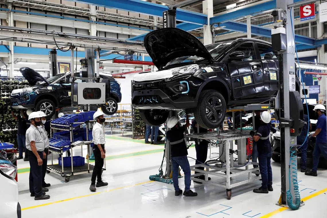 Workers inspecting electric vehicles (EVs) at a Tata Motors plant in Pune, India. 