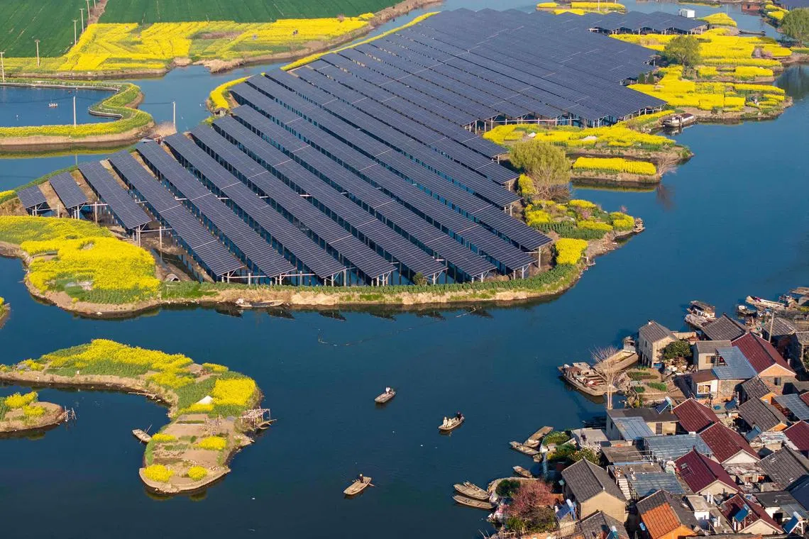 (FILES) An aerial view shows solar panels next to rapeseed fields at a village in Taizhou, in China's eastern Jiangsu province on on March 26, 2025. China's emissions fell in the first quarter of 2025 despite rapidly growing power demand thanks to soaring renewable and nuclear energy, a key milestone for world's top emitter, analysis showed on May 15. (Photo by AFP) / - China OUT