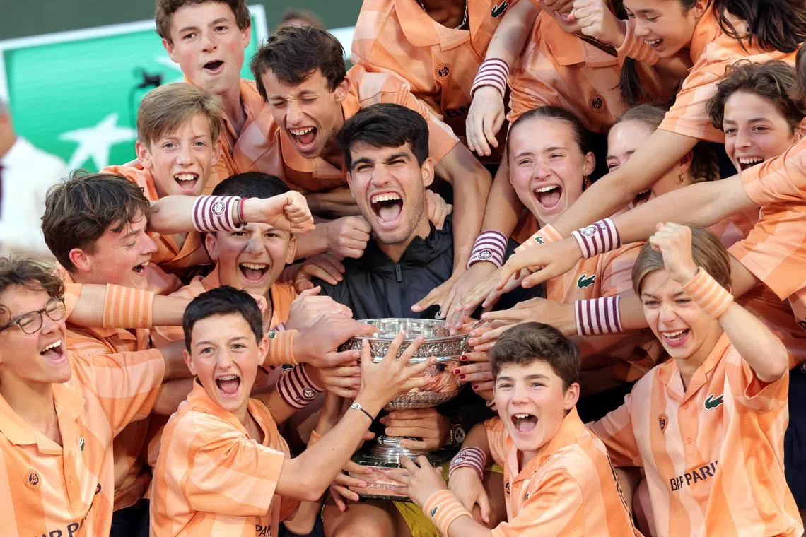 Carlos Alcaraz of Spain posing with the Coupe des Mousquetaires trophy and ball kids after winning his French Open men’s singles final match against Alexander Zverev of Germany at Roland Garros on June 9.
