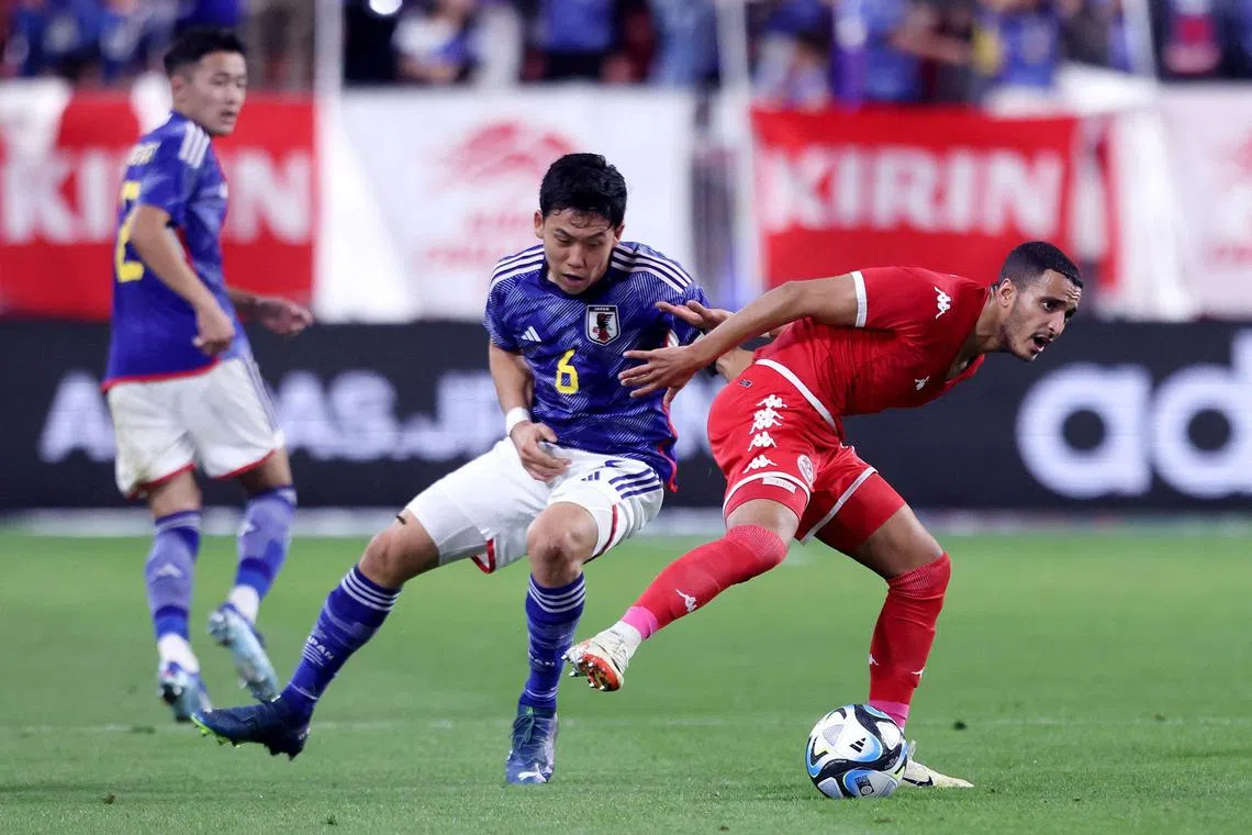 Japan's Wataru Endo competes for the ball with Tunisa's Elies Ashley during a friendly match.