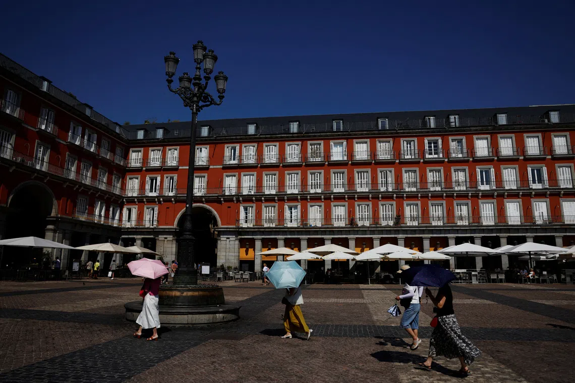 FILE PHOTO: Tourists cover themselves with umbrellas while visiting Plaza Mayor square during a heatwave in Madrid, Spain, August 4, 2025. REUTERS/Susana Vera/File Photo