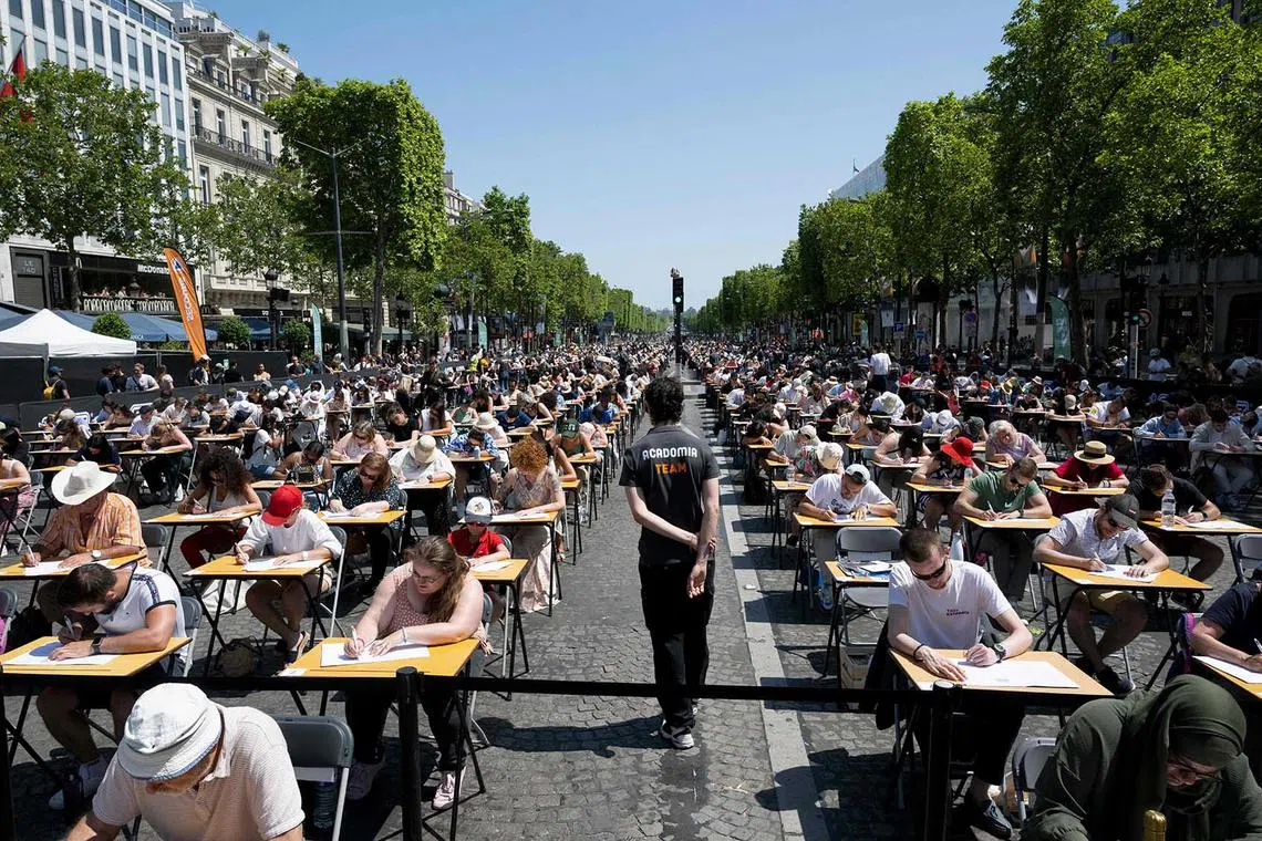 Participants attempt to beat the record of the "World's Biggest Dictation" on the prestigious Champs-Elysees Avenue, transformed into a giant classroom, in Paris on June 4.