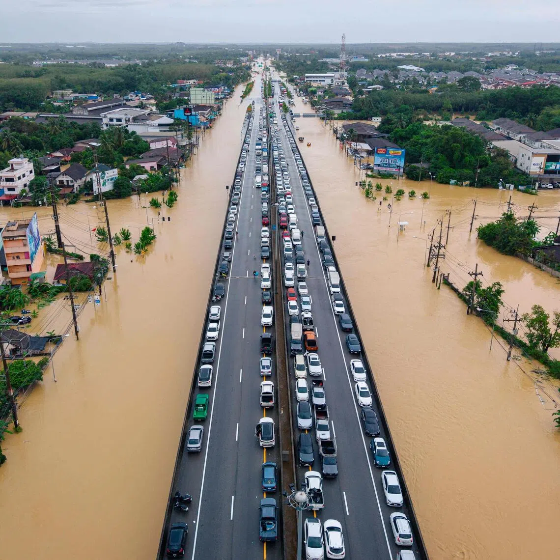 Vehicles park on an elevated road to keep them out of flood waters in Hat Yai in Thailand.