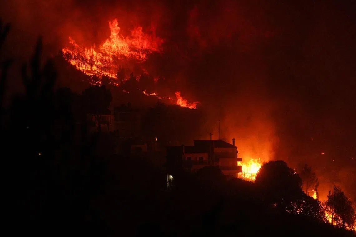 Flames from a wildfire threaten residential properties in Dionysos, Greece, on Aug 12.