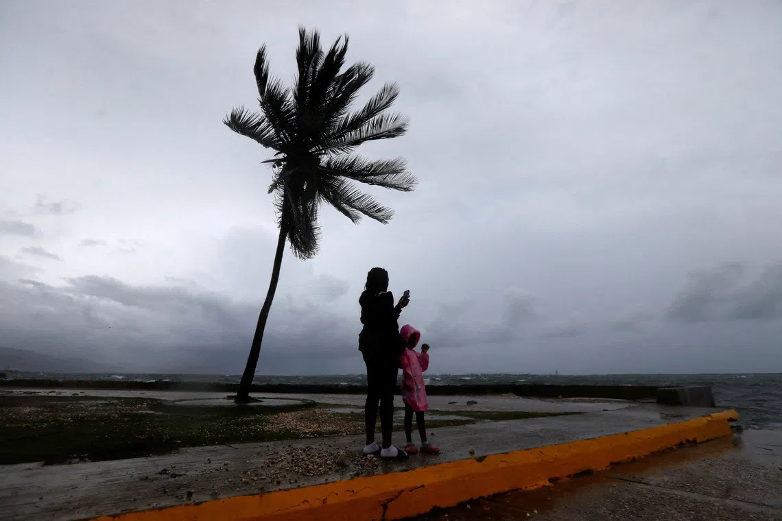 A woman and a child stand along the Kingston waterfront as Hurricane Melissa approaches, in Kingston, Jamaica, October 27, 2025.  REUTERS/Octavio Jones