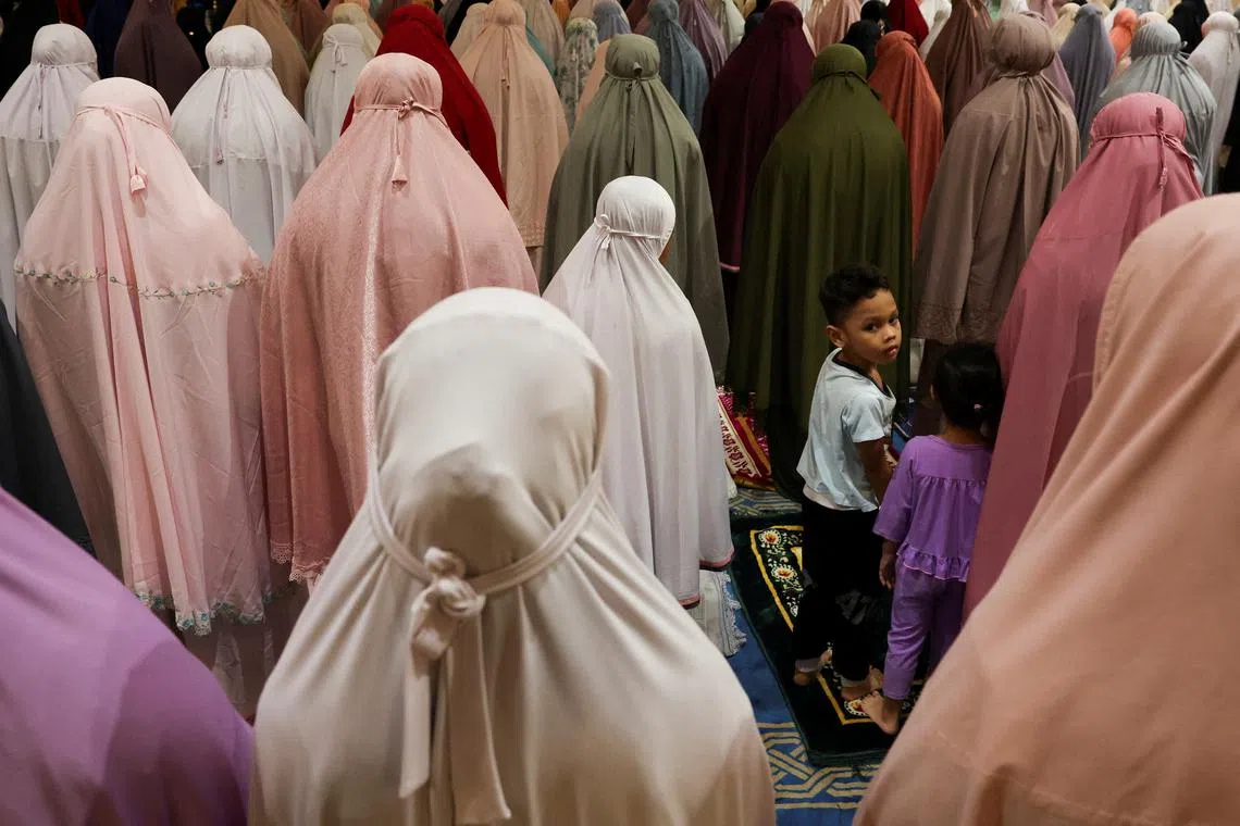 Kids standing amongst Muslim women who are performing the mass prayer of Tarawih during the first eve of the holy fasting month of Ramadan at Seremban, Malaysia, Mar 11, 2024. 