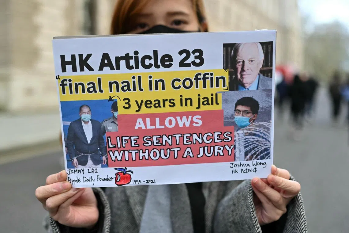 An activist holds a placard protesting Hong Kong’s new security law known as Article 23.