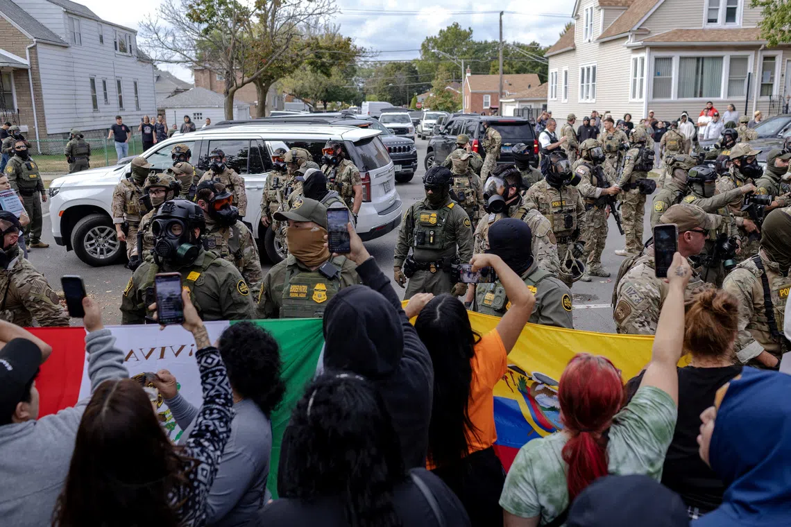 FILE PHOTO: Federal agents stand guard as community members gather near a car crash site where agents detained a man on Chicago?s South Side, in Chicago, Illinois, U.S., October 14, 2025, after U.S. President Donald Trump ordered increased federal law enforcement presence to assist in crime prevention.  REUTERS/Jim Vondruska/File Photo