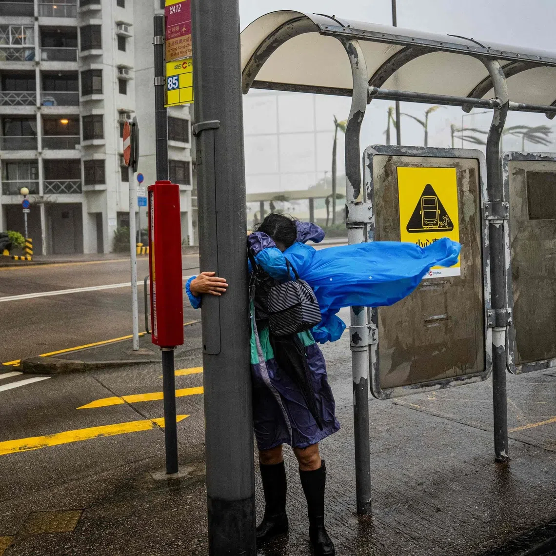A woman holding on to a lamp post in Hong Kong as Super Typhoon Ragasa hits the city on Sept 24.