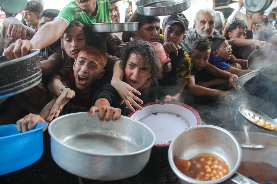 FILE PHOTO: Palestinians gather to receive food cooked by a charity kitchen, amid the Israel-Hamas conflict, in the northern Gaza Strip, September 11, 2024. REUTERS/Mahmoud Issa/File Photo