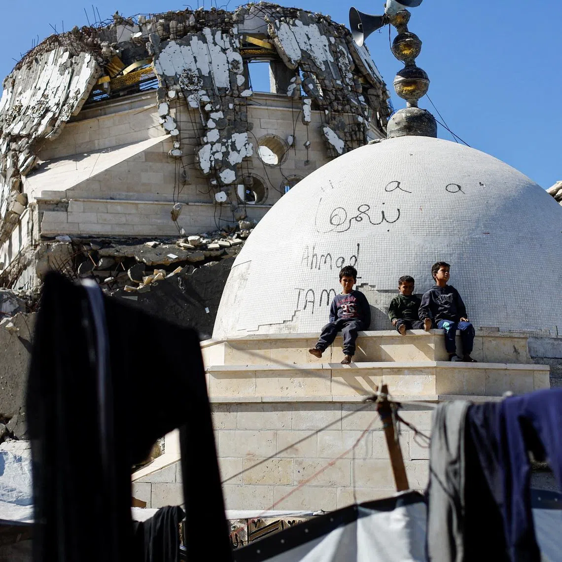 Palestinian children sit atop the rubble of a mosque destroyed during the two-year Israeli offensives, in Gaza City on Feb 11.