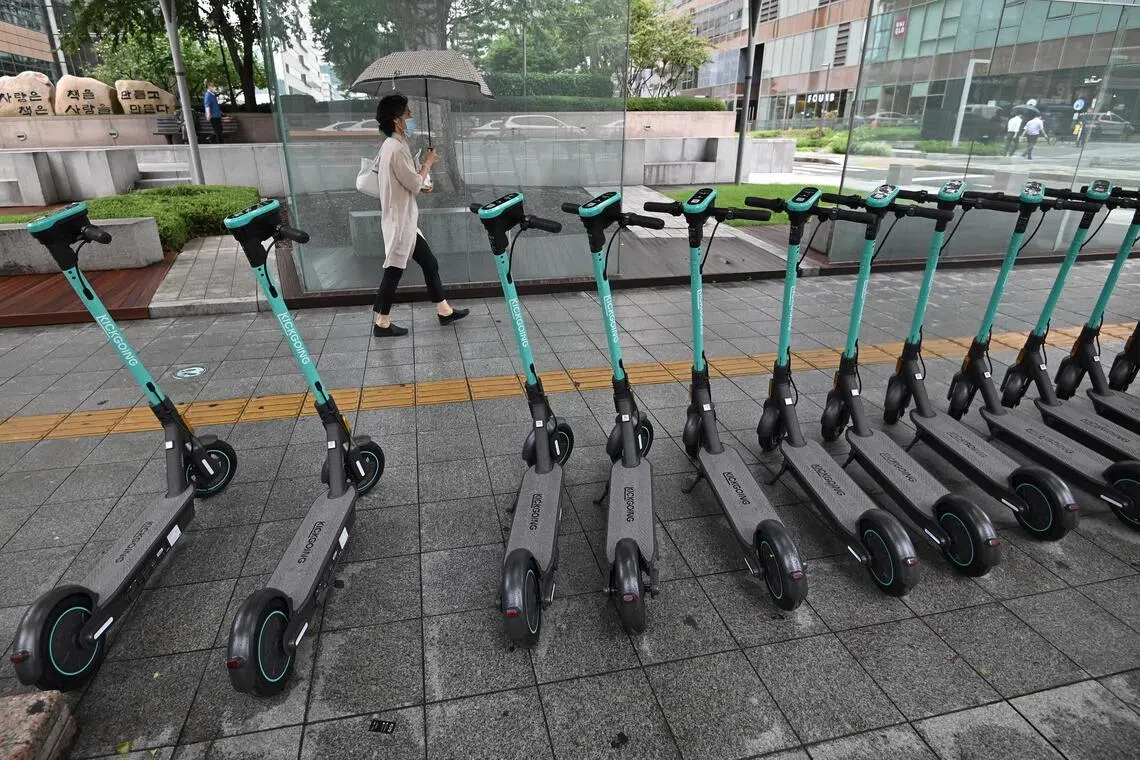 A woman walks past electric kickboards parked on a street in central Seoul on July 23, 2020. South Korea's economy recorded its worst performance in more than 20 years in the second quarter, the central bank said on July 23, as the coronavirus pandemic hammered its exports. (Photo by Jung Yeon-je / AFP)