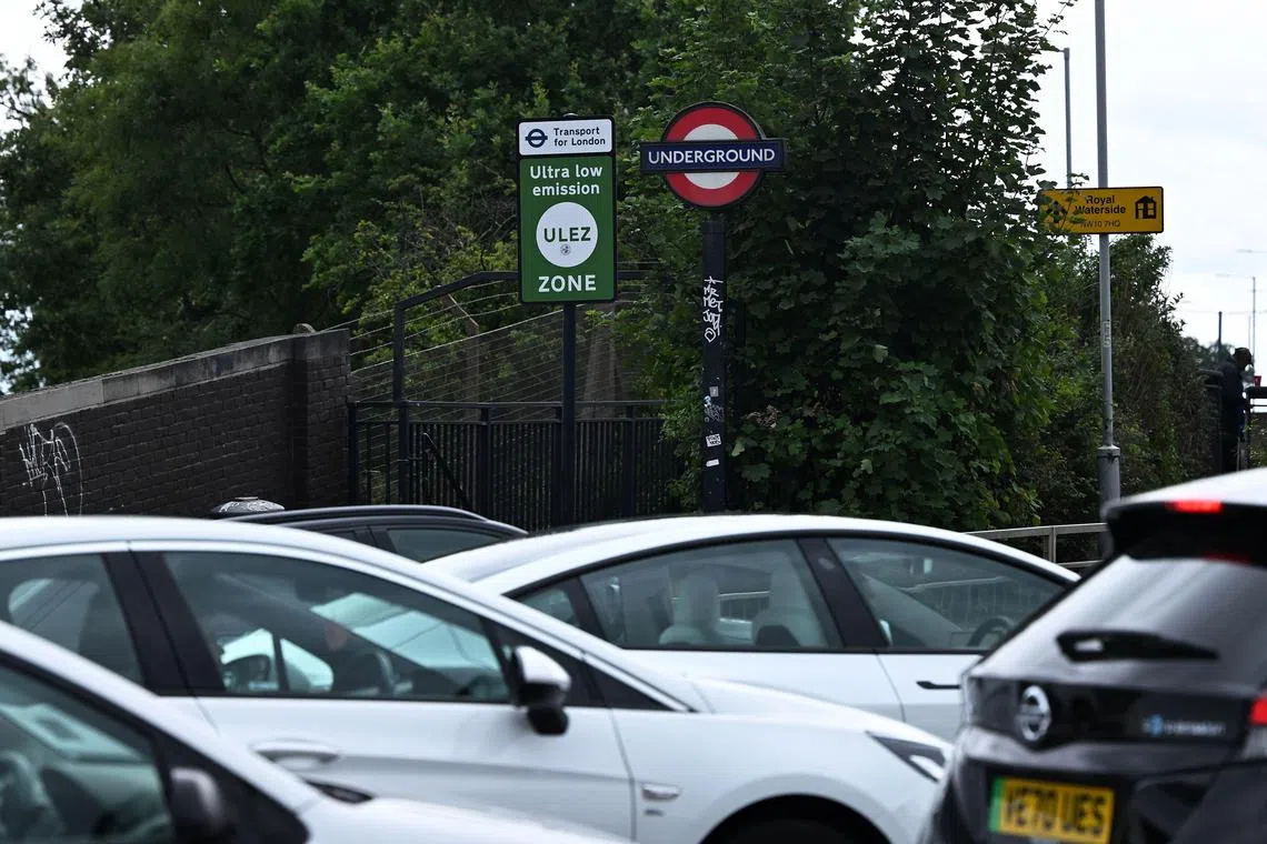 Cars pass a sign indicating the ultra-low emission zone (ULEZ) at Hanger Lane in west London on July 22, 2023. Sadiq Khan intends to expand the Ultra-Low Emission Zone (ULEZ) to the whole of the British capital on August 29 -- barring a last-ditch High Court bid to stop it. The scheme -- first introduced in inner London in 2019 and separate from its two-decades-old congestion charge -- requires more polluting vehicles to pay a £12.50 ($16) toll on days they are driven within its borders. (Photo by JUSTIN TALLIS / AFP)