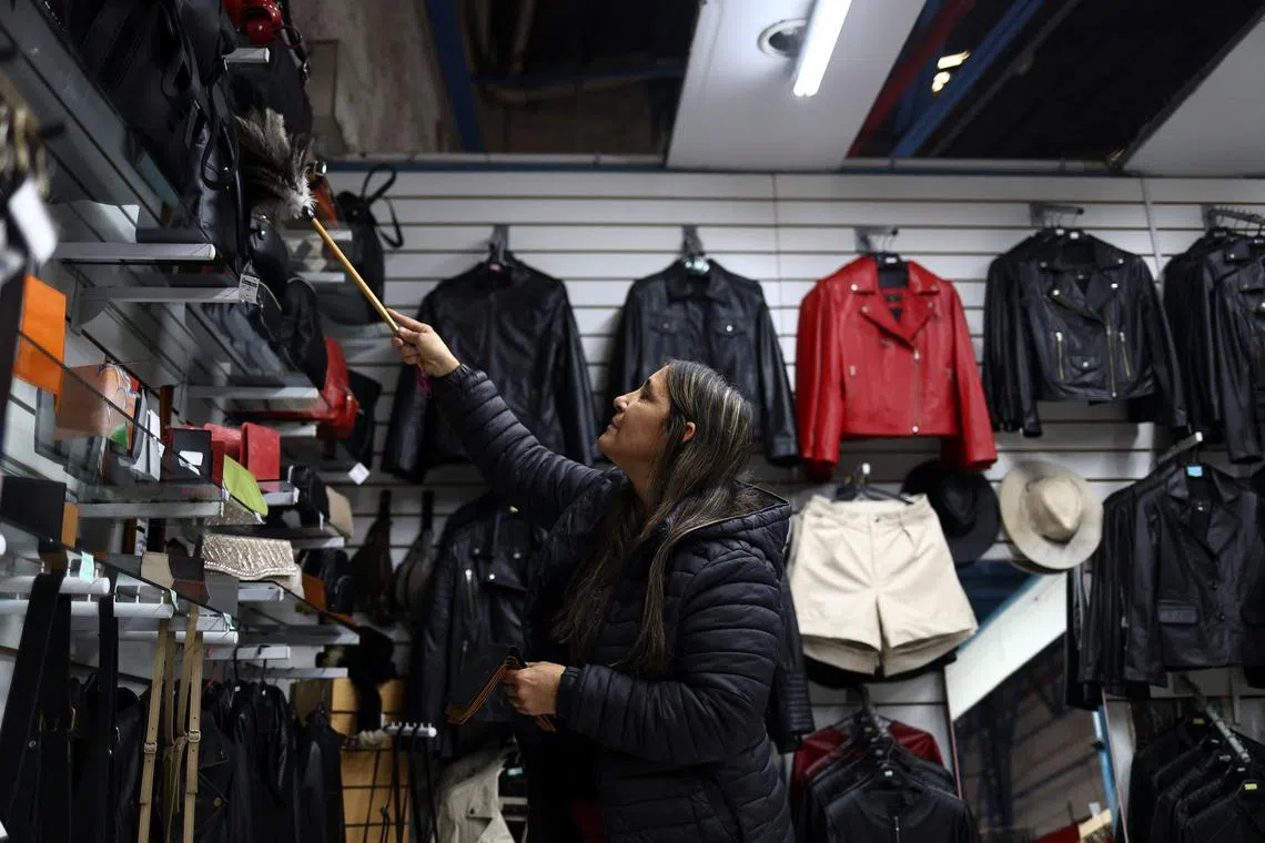 A woman cleans with a duster at a clothing store, as Argentina is battling inflation that is running on an annual basis above 275%, in Buenos Aires, Argentina, April 11, 2024. REUTERS/Matias Baglietto/File Photo