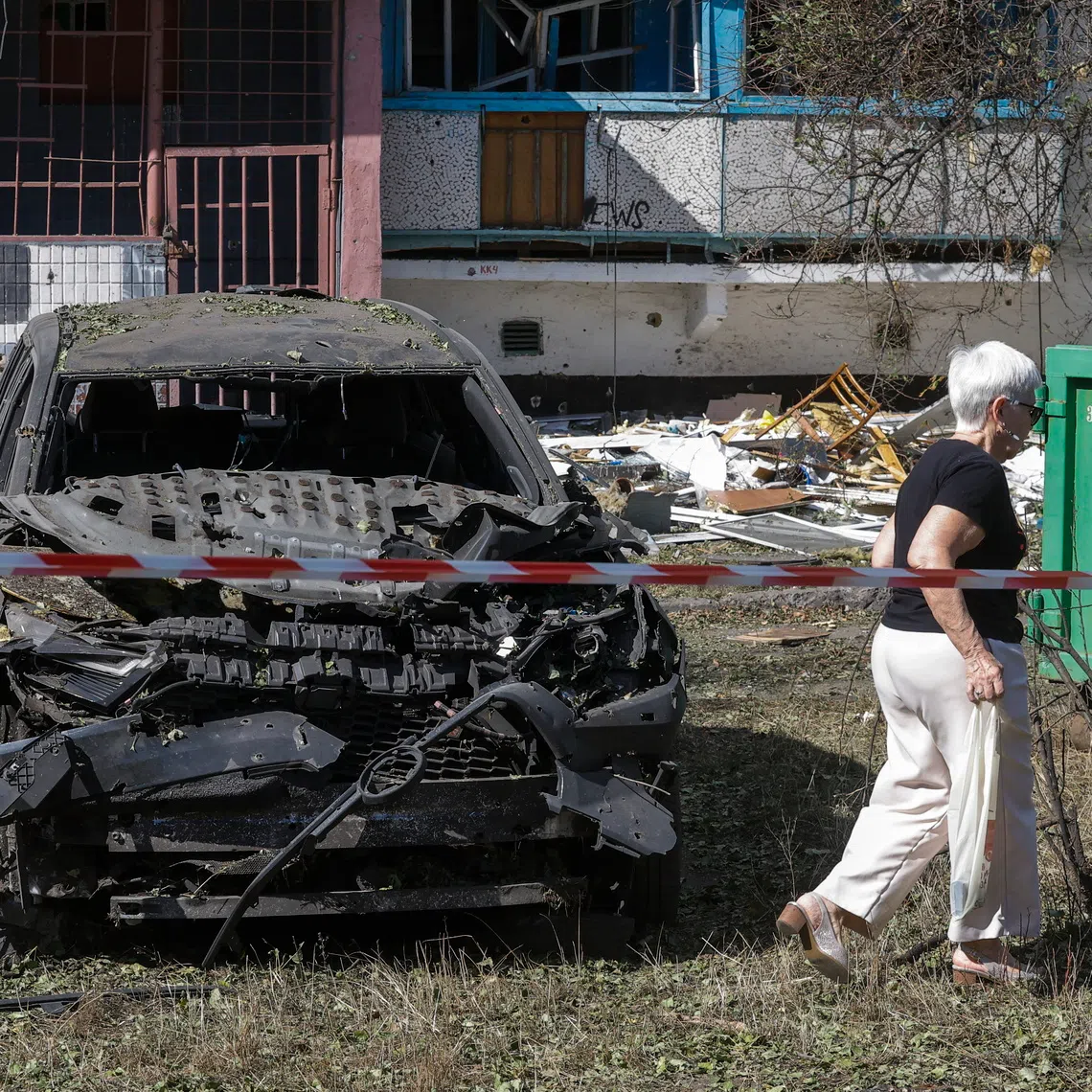 A woman walking past a damaged car at the site of a Russian strike on a high-storey residential building in Kyiv, Ukraine, on Sept 17.