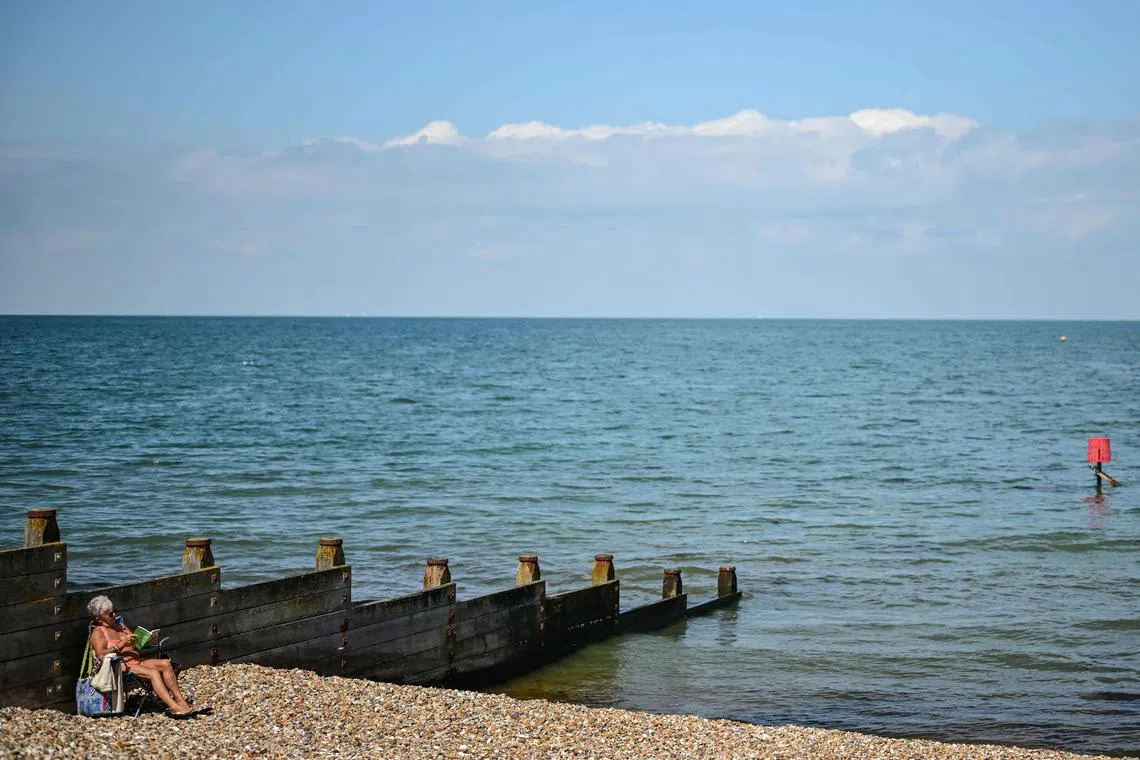 A person sits on Tankerton beach in Whitstable, south east England, on July 23, 2025. "Every time we go to the beach, we wonder if we can go in the water." In the seaside town of Whitstable, in south-east England, the local water company's sewage discharges are a constant source of concern for residents. As elsewhere in the United Kingdom, the company that manages water treatment is authorised to discharge excess water into the sea when the network is saturated, for example in the event of rain. (Photo by Ben STANSALL / AFP)