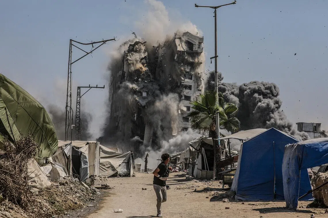 A boy running as a building collapses following an Israeli air strike in the west of Gaza City on Sept 5.