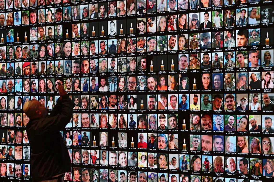 A visitor takes pictures of a giant screen bearing the portraits of the people killed during the Oct 7 attacks by Hamas.