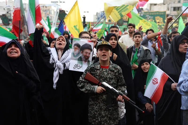 A young enthusiast dressed in military attire holding a mock rifle at a rally in support of the Iran's Supreme Leader Ayatollah Mojataba Khamenei in Tehran, on April 29.