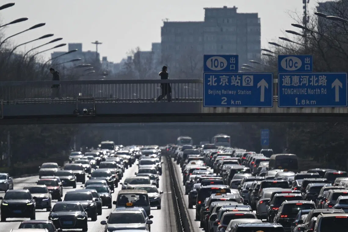 Pedestrians walk along an overpass as traffic snarls in Beijing on Feb 11. 