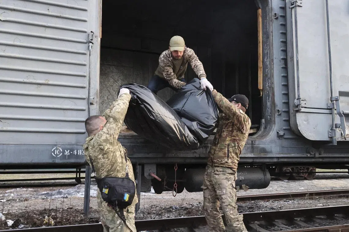 Special team members load the dead body of a Russian soldier into a refrigerated wagon in Ukraine's  Kharkiv region.