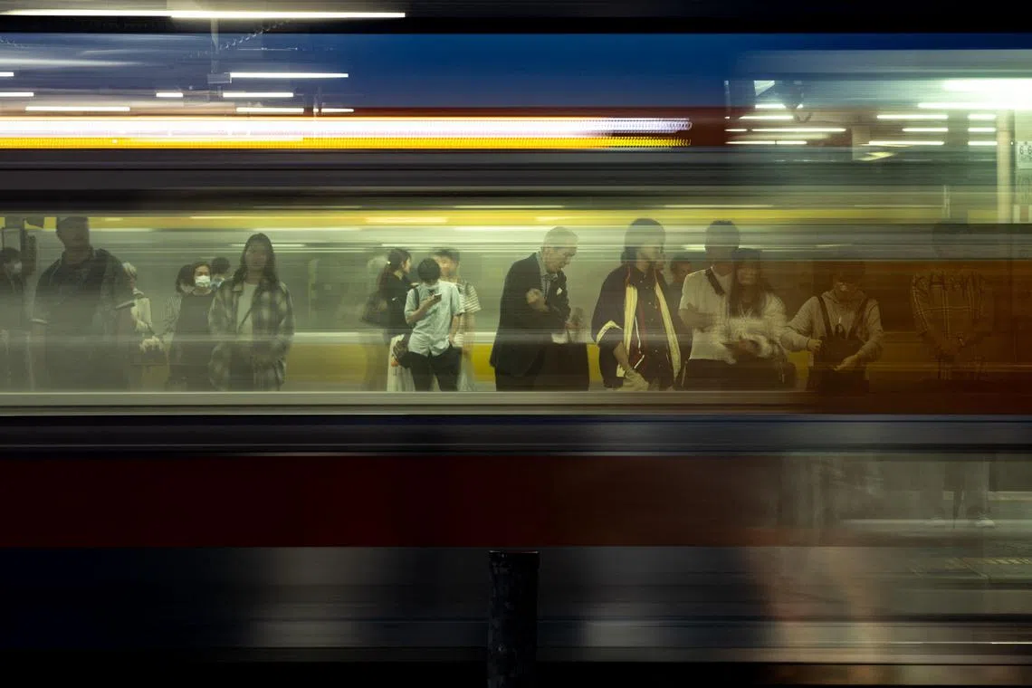 TOPSHOT - A train travels by as passengers wait on a platform of Nakano station during the evening hour in Tokyo on June 14, 2025. (Photo by Philip FONG / AFP)