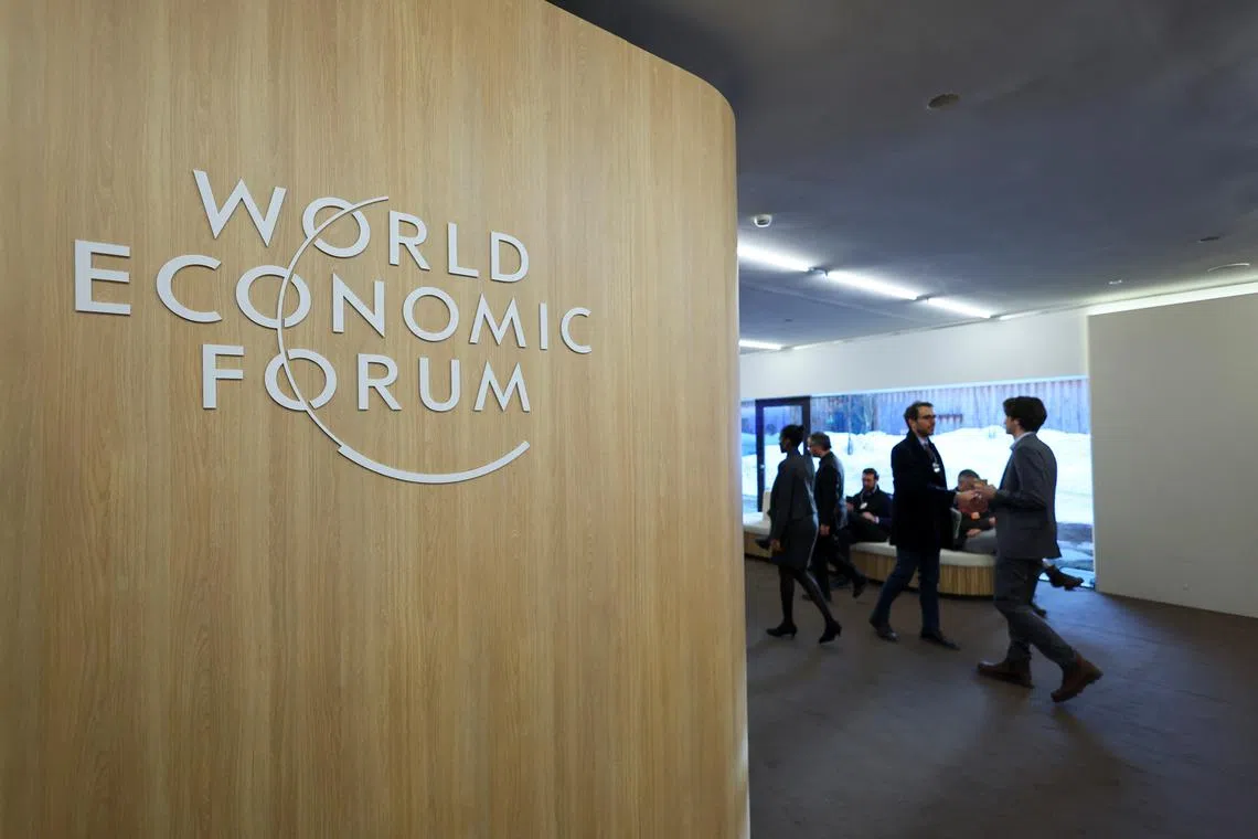 FILE PHOTO: People walk next to the logo of World Economic Forum (WEF) on the first day of the annual meeting in Davos, Switzerland, January 15, 2024. REUTERS/Denis Balibouse/File Photo