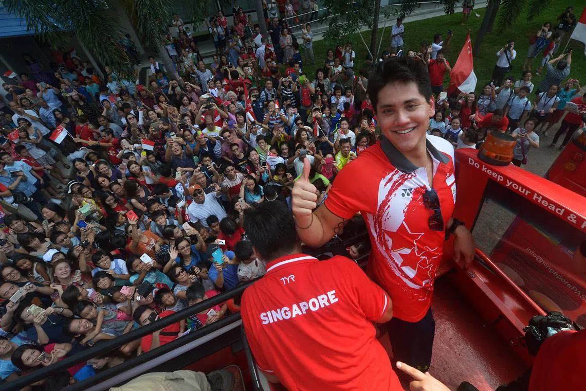 Singapore's first Olympic champion, Joseph Schooling, posing for media photographers atop the victory bus as it left Block 50A Marine Terrace market on Aug 18, 2016.